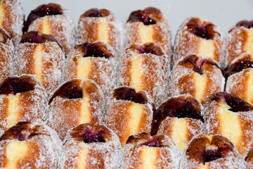 Many donuts placed in a tray, for sale at food market.