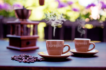 Morning cup of hot coffee. Steam over the cup. Coffee beans and coffee grinder.