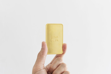 Hand holding 96.5 percent gold bar, isolated on white background
