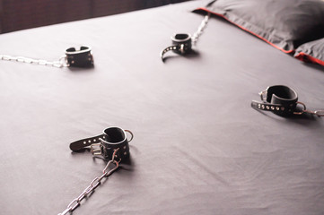 BDSM Leather handcuffs for role-playing games on a gray sheet. Bondage for carnal pleasures....