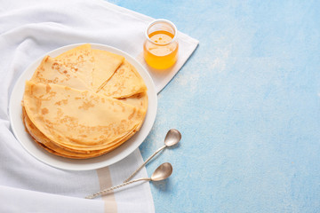 Tasty blini with honey on color background