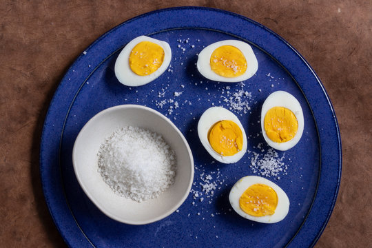 two half boild eggs on a blue plate with rock salt
