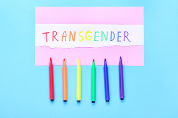 Paper with word TRANSGENDER and markers on color background