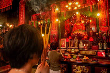 Chinese people praying in the Buddhist temple with incense sticks