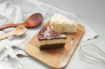 Chocolate beautiful cake and pancake cake on a wooden stand on the kitchen light table with a whisk, wooden spoons and a waffle towel. Homemade beautiful Breakfast