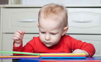 Small toddler or a baby child playing with puzzle shapes on a low table in a colorful children room in a nursery or preschool