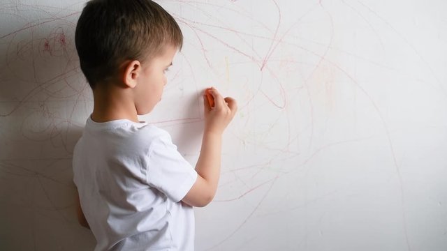 Boy draws on the wall with colored chalk. The child is engaged in creativity at home