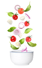 Mozzarella cheese, tomatoes, onion and basil leaves falling into bowl on white background