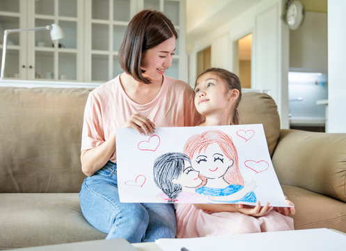 little girl showing  Color pencil drawing family picture to her mother and celebrating mothers day