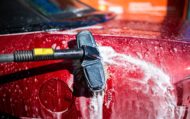 Hand washing with brush and compressor of a red car.