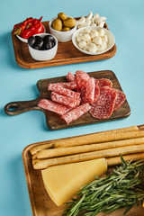 High angle view of antipasto ingredients on boards on blue background