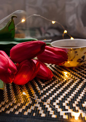 a bouquet of red tulips with a cup of aromatic tea or delicious coffee