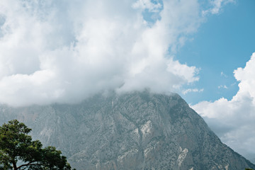 A group of clouds in the sky with a mountain in the background