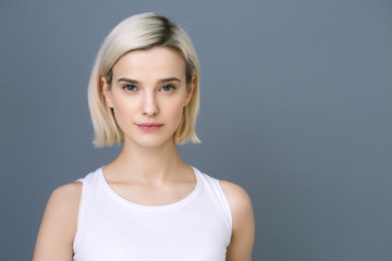 Obraz premium Beautiful woman blonde short hair natural casual make up over gray wall