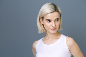 Obraz premium Beautiful woman blonde short hair natural casual make up over gray wall