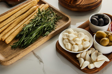 High angle view of boards with breadsticks, rosemary and antipasto ingredients on white background