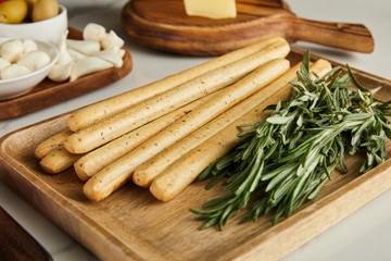Selective focus of boards with breadsticks, rosemary and antipasto ingredients on white