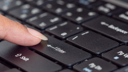 Press the finger on the laptop keyboard. 
Working or studying online concept.