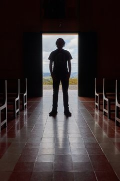 Silhouette of a mans standing at the church entrance, dark, unrecognizable interior