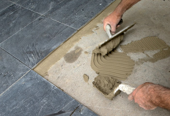 Laying tiles. Plastering concrete at the florr to attach the tiles