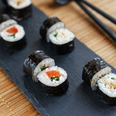 Sushi on a black stone board. Fresh set of sushi with salmon and avocado.