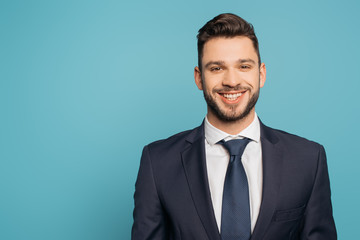 cheerful, handsome businessman smiling at camera isolated on blue