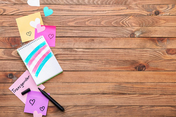 Notebook with drawing of transgender flag on wooden background