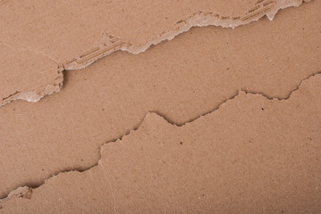 Old textured cardboard sheet with torn edges. Brown cardboard torn off. Cardboard texture. A sheet of tattered cardboard lies on a whole sheet of cardboard