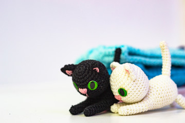 Knitted little black and white kitten on a white background. Hand knitted toy. Amigurumi. blurred colored background