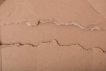 Old textured cardboard sheet with torn edges. Brown cardboard torn off. Cardboard texture. A sheet of tattered cardboard lies on a whole sheet of cardboard