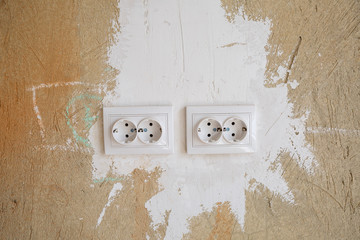 White outlets on concrete wall during repair. Installation of sockets during repair in fresh cement empty walls