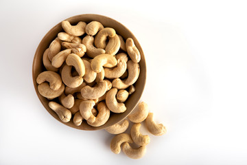 Cashew nuts in a brown bowl on a white background