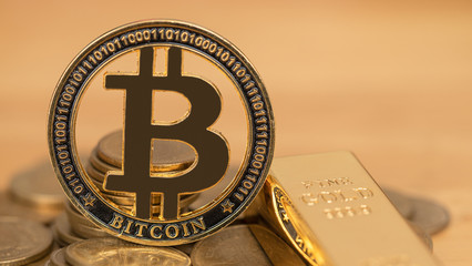 Bitcoin coin and gold bar Placed on  pile of money. Concept Investors will accumulate gold or...