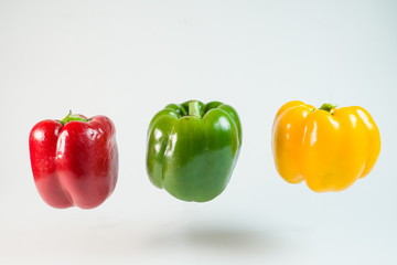 Close up of red and yellow peppers fly on air isolated on white background 