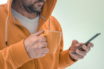 Man drinking coffee and using mobile phone in morning