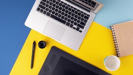 Laptop with a graphics tablet and notes everywhere on work place. Top view workspace. Stop motion animation
