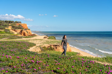 Athletic girl practices walking jogging on the rocky shore of the Atlantic Ocean. Portugal Algarve...