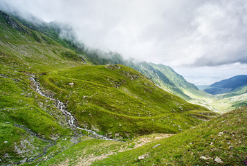 Summer landscape. Mountain stream. Clouds over the mountain