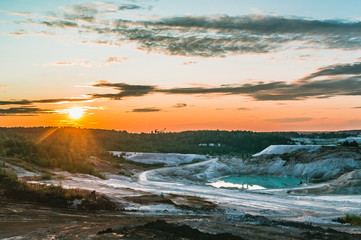 Sunset over half-flooded kaolin quarry surrounded by woods in Hlukhivtsi, Ukraine