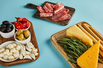 High angle view of salami slices and antipasto ingredients on boards on blue