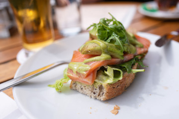 Fetta di pane con fette di salmone, crema di avocado e rucola servita su un piatto