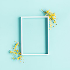 Flowers composition. Photo frame, yellow flowers on blue background. Spring concept. Flat lay, top...