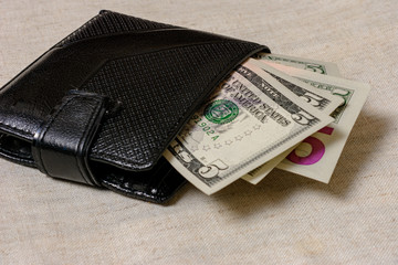 A dollar bill in the size 5 of a black wallet.