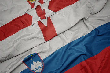 waving colorful flag of slovenia and national flag of northern ireland.
