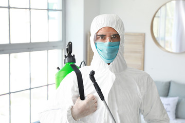 Fototapeta na wymiar Worker in biohazard suit disinfecting house