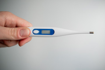 Obraz premium man holds a medical thermometer in his hand