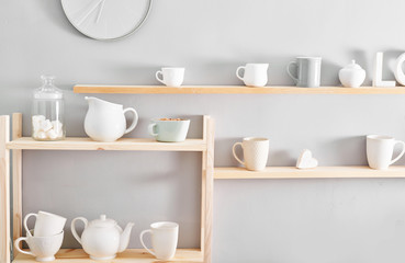Fototapeta na wymiar Utensils and mugs on shelf. Dishes in cupboard in kitchen.