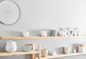 Utensils and mugs on shelf. Dishes in cupboard in kitchen.
