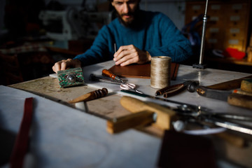 A leather craftsman works in a workshop. 