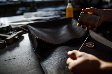 A leather craftsman works in a workshop. 